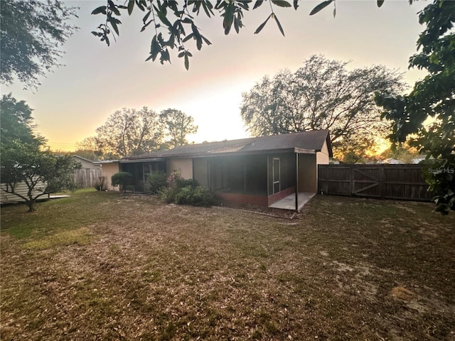 back house at dusk featuring a yard