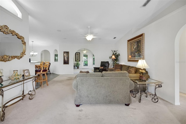 carpeted living room with ceiling fan with notable chandelier