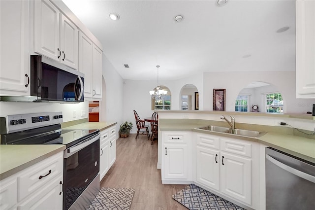 kitchen featuring appliances with stainless steel finishes, sink, light hardwood / wood-style flooring, white cabinetry, and hanging light fixtures