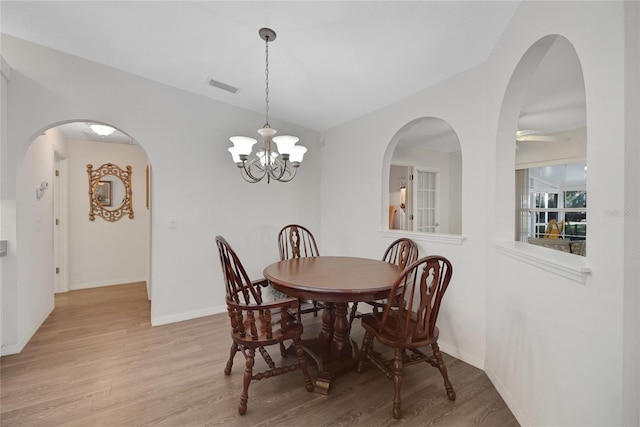 dining room featuring a chandelier, lofted ceiling, and light wood-type flooring