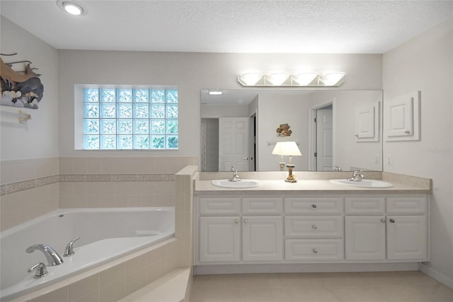 bathroom featuring vanity, a textured ceiling, and tiled tub