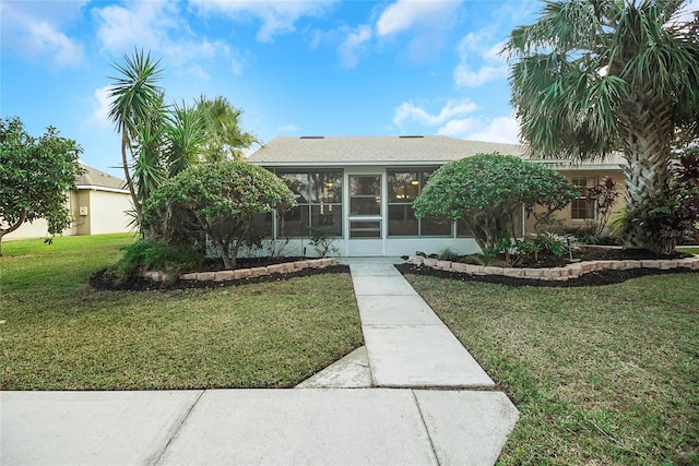 view of front facade with a front yard and a sunroom