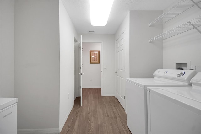 laundry room with light wood-type flooring and separate washer and dryer