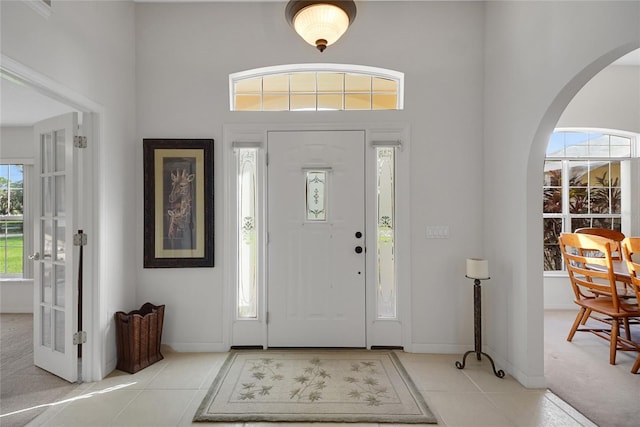 carpeted entryway featuring a high ceiling and plenty of natural light