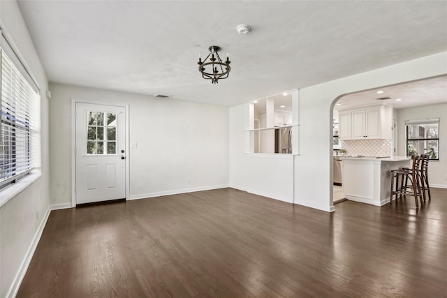 unfurnished living room featuring dark hardwood / wood-style floors and an inviting chandelier