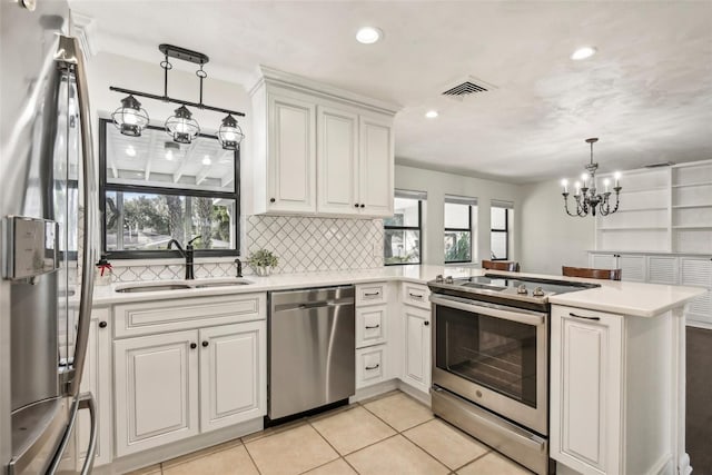 kitchen with kitchen peninsula, stainless steel appliances, a healthy amount of sunlight, and sink