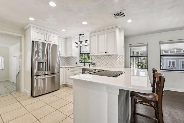 kitchen with kitchen peninsula, stainless steel fridge with ice dispenser, decorative light fixtures, and white cabinetry