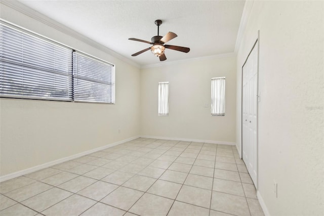 tiled empty room with ceiling fan and crown molding