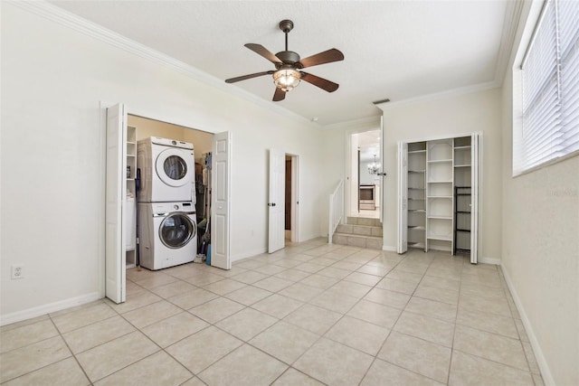 clothes washing area featuring ceiling fan, stacked washer / dryer, a textured ceiling, light tile patterned floors, and ornamental molding