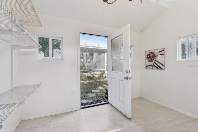 doorway with light tile patterned floors, lofted ceiling, and a wealth of natural light