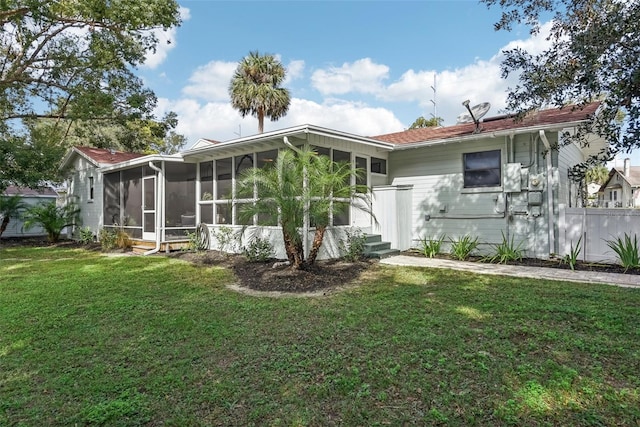 rear view of house featuring a sunroom and a yard