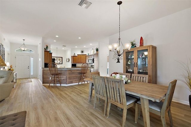 dining space with light hardwood / wood-style floors and an inviting chandelier