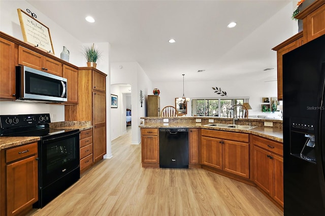 kitchen featuring light stone countertops, sink, black appliances, and light hardwood / wood-style flooring