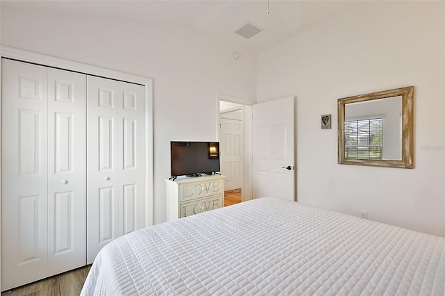 bedroom featuring lofted ceiling, light hardwood / wood-style flooring, and a closet