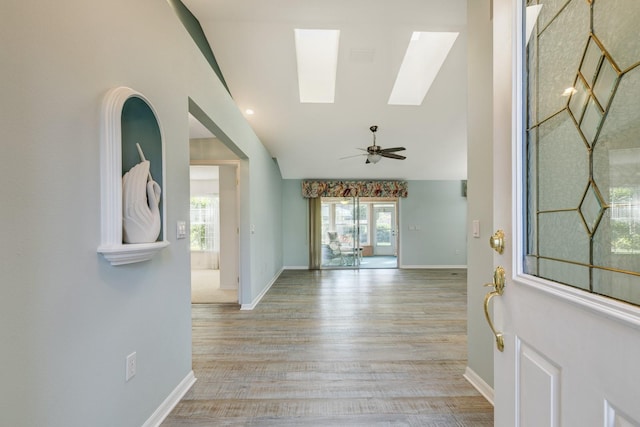 foyer entrance featuring light hardwood / wood-style floors, lofted ceiling with skylight, and ceiling fan