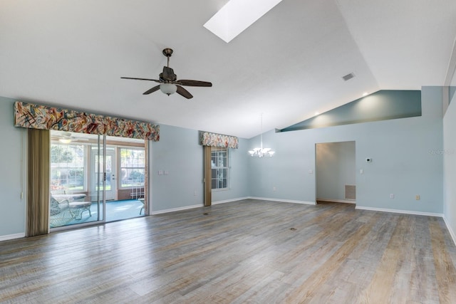 empty room with vaulted ceiling with skylight, ceiling fan with notable chandelier, and light hardwood / wood-style floors