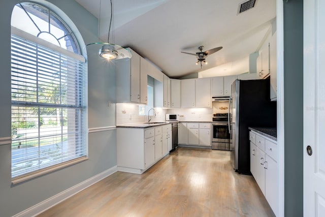 kitchen featuring white cabinets, vaulted ceiling, and a wealth of natural light