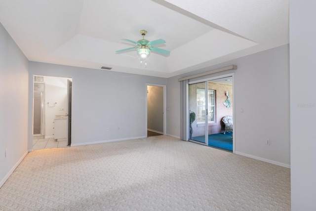 unfurnished room featuring a tray ceiling, ceiling fan, and light colored carpet