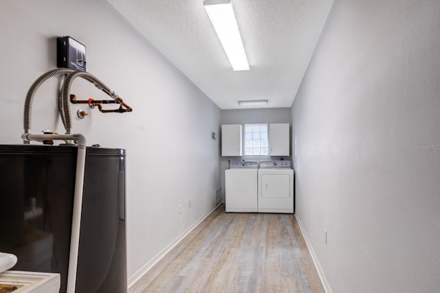 laundry room with a textured ceiling, light hardwood / wood-style flooring, and washing machine and clothes dryer