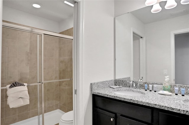 bathroom featuring vanity, a shower with shower door, and toilet