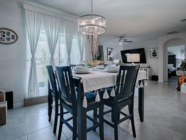 tiled dining space featuring ceiling fan with notable chandelier