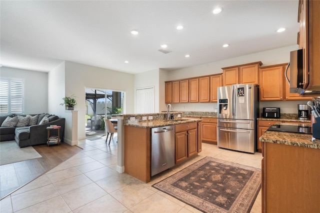 kitchen featuring stainless steel appliances, a kitchen island with sink, light tile patterned flooring, and plenty of natural light