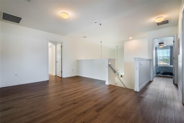 empty room with dark hardwood / wood-style flooring, a textured ceiling, and ceiling fan