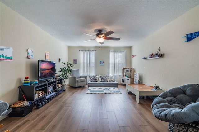 living room with ceiling fan, hardwood / wood-style floors, and a textured ceiling