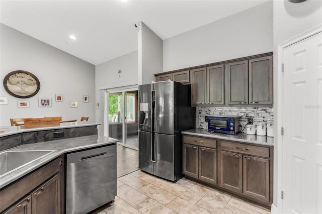 kitchen with backsplash, high vaulted ceiling, sink, appliances with stainless steel finishes, and dark brown cabinetry