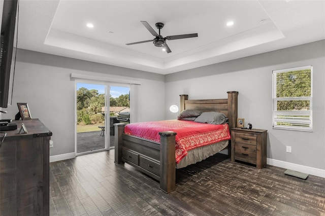 bedroom featuring dark hardwood / wood-style floors, ceiling fan, a raised ceiling, and access to outside