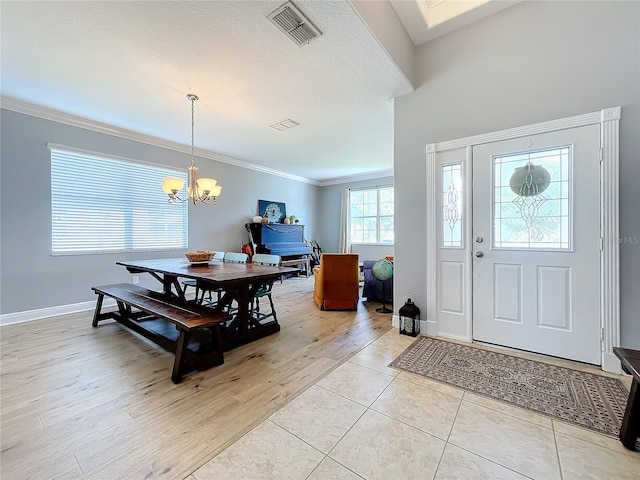 entrance foyer featuring crown molding, light hardwood / wood-style floors, a textured ceiling, and a notable chandelier