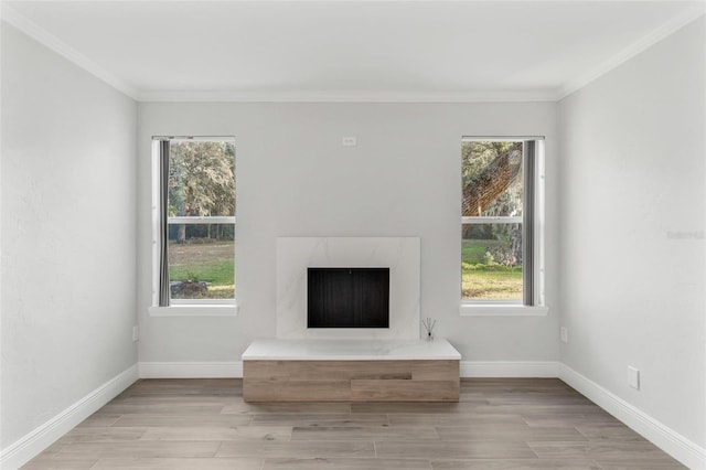 unfurnished living room with light hardwood / wood-style floors, ornamental molding, and a high end fireplace