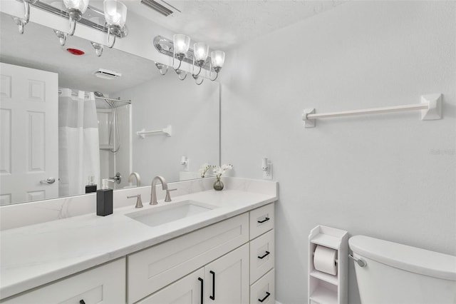 bathroom with a textured ceiling, vanity, toilet, and walk in shower