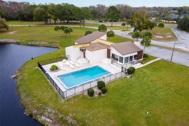 view of pool with a patio area, a water view, and a lawn