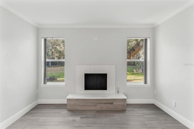 unfurnished living room featuring light hardwood / wood-style floors, crown molding, and a wealth of natural light