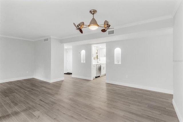 empty room with ornamental molding, ceiling fan, sink, and hardwood / wood-style floors