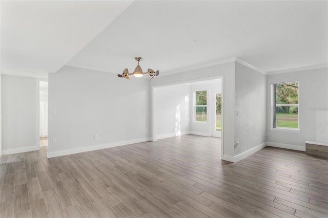 unfurnished living room with crown molding, a chandelier, a healthy amount of sunlight, and light hardwood / wood-style flooring