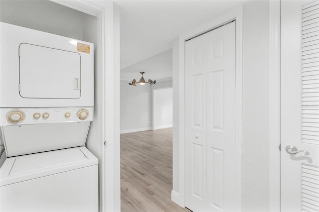 laundry area with light hardwood / wood-style floors and stacked washer and clothes dryer