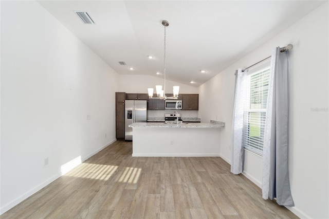 kitchen with appliances with stainless steel finishes, dark brown cabinets, vaulted ceiling, sink, and light hardwood / wood-style flooring