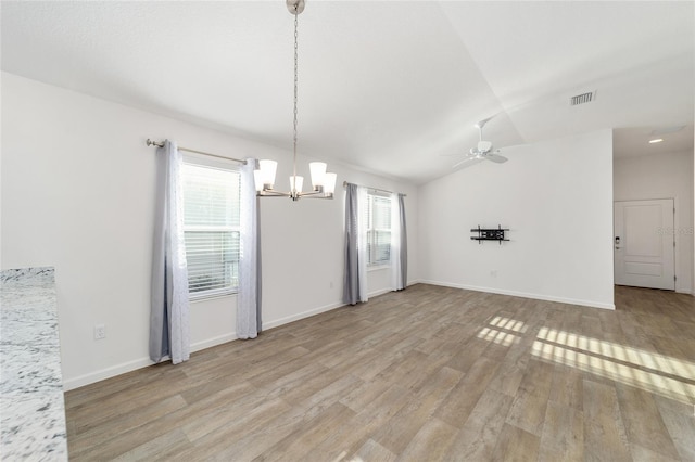 unfurnished dining area featuring ceiling fan with notable chandelier, lofted ceiling, and light hardwood / wood-style flooring