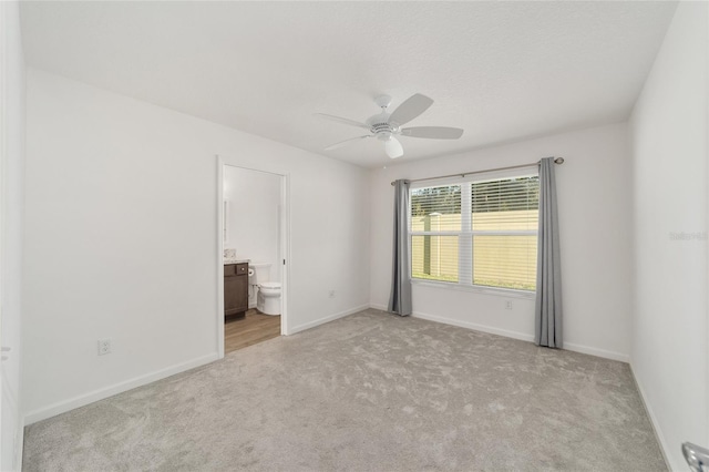 unfurnished bedroom featuring light carpet, connected bathroom, and ceiling fan