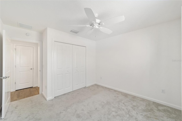 unfurnished bedroom featuring ceiling fan, a closet, and light colored carpet