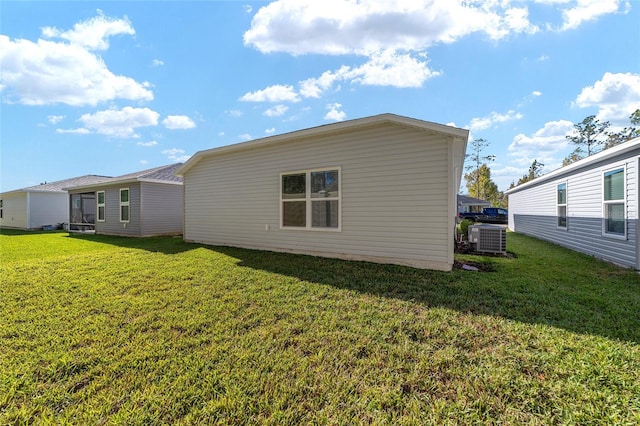 back of property featuring cooling unit and a lawn