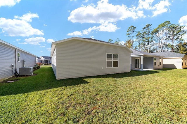 rear view of house featuring central AC unit and a yard