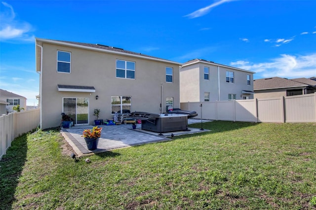 rear view of house with a hot tub, a patio, and a lawn