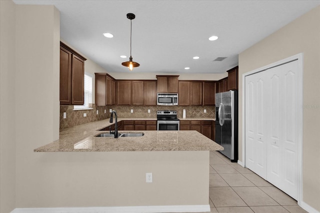 kitchen with sink, appliances with stainless steel finishes, decorative light fixtures, light tile patterned flooring, and kitchen peninsula