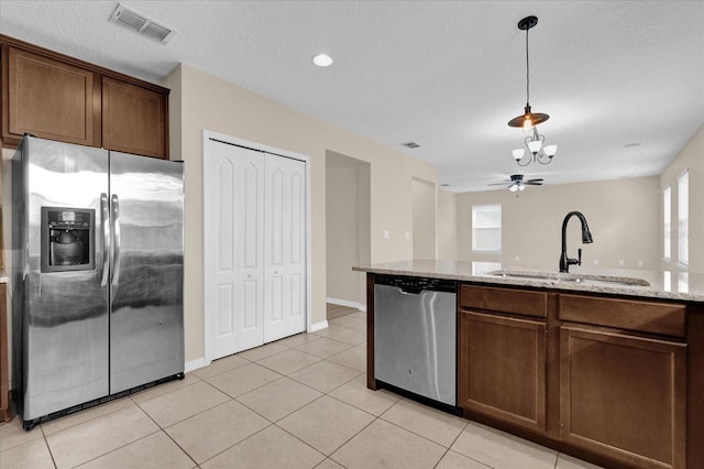 kitchen featuring pendant lighting, sink, light tile patterned flooring, light stone counters, and stainless steel appliances