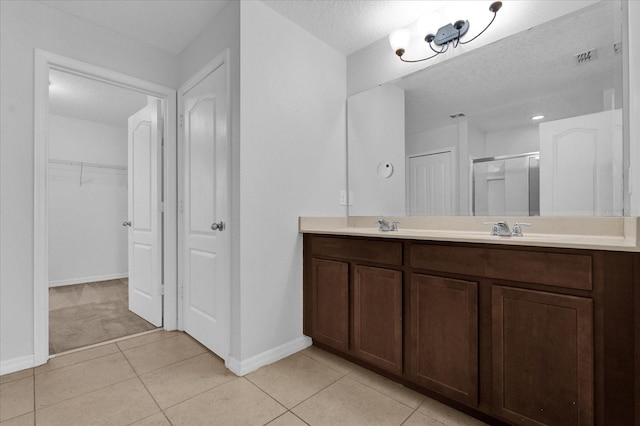 bathroom featuring tile patterned flooring, vanity, a textured ceiling, and a shower with shower door