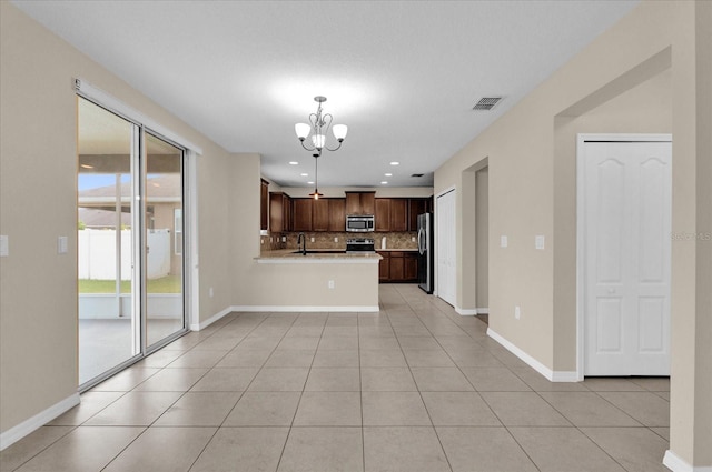 kitchen featuring hanging light fixtures, stainless steel appliances, decorative backsplash, and light tile patterned flooring