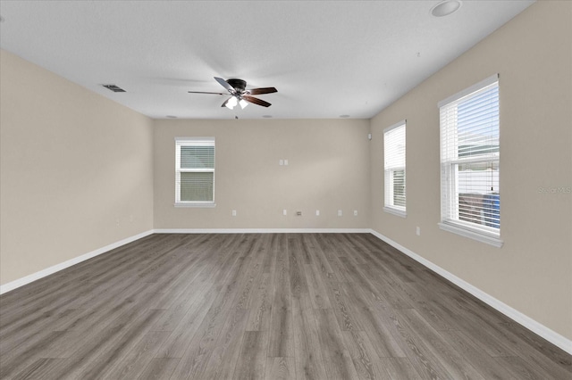 unfurnished room featuring visible vents, baseboards, and wood finished floors